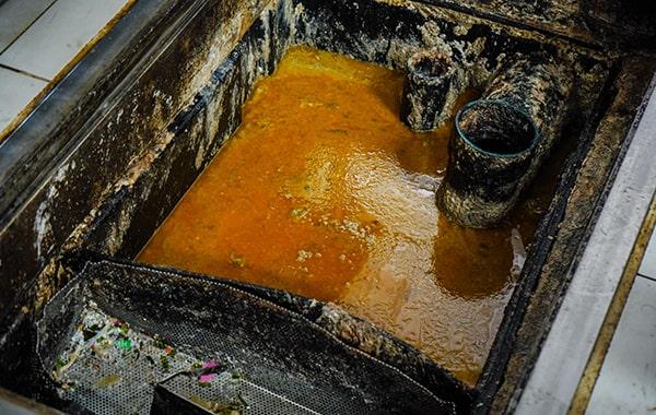 during grease trap cleaning, the trap is cleared, scraped, and cleaned to remove built-up grease and solids